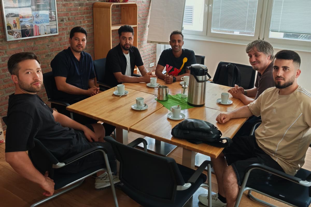 Team und junge Menschen sitzen gemeinsam am Tisch in der Berg Tabor Basis